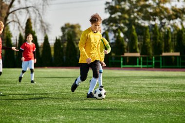 Sahada futbol oynayan bir grup genç çocuk var. Koşuyorlar, tekmeliyorlar, pas veriyorlar ve topa beceri ve heyecanla vuruyorlar..
