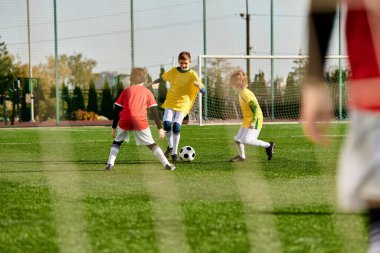 Bir grup genç çocuk, enerji ve coşku dolu, çimenli bir alanda yoğun bir futbol oyunu oynuyorlar. Tekmeliyorlar, koşuyorlar ve pas veriyorlar, takım çalışması ve sportmenlik sergiliyorlar..