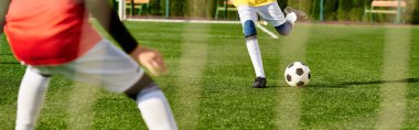 Enerji dolu genç bir çocuk yeşil bir sahada bir futbol topunu ustalıkla tekmeliyor. Topun kontrolünü tamamen elinde tutuyor, büyük bir teknik sergiliyor ve hareketlerine odaklanıyor..