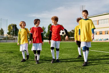 Futbol sahasının tepesinde gururla duran bir grup genç çocuk zaferlerini gülümseyerek ve beşlik çakarak kutluyorlar..