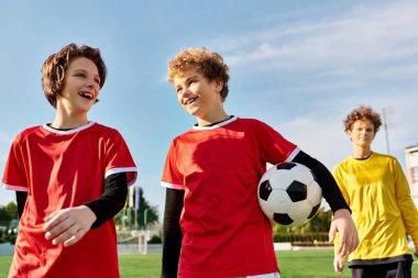 Bir futbol sahasında yan yana duran bir grup genç adam, ilerideki maça hazırlanırken dostluk ve takım çalışması hissi sergiliyorlar..