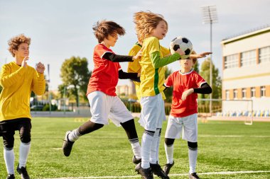Çeşitli bir grup genç çocuk hevesle futbol oynuyorlar. Koşuyorlar, topa vuruyorlar ve birbirlerine tezahürat yapıyorlar. Güneş parlıyor ve çimenler canlı yeşil..