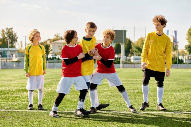 Bir grup genç, zorlu bir maçın ardından sevinçle futbol sahasının tepesinde duruyor. Zaferlerini kutlarken yoldaşlıkları ve başarıları parlıyor..