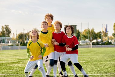 Bir grup enerjik genç erkek, canlı yeşil bir futbol sahasında, yüzleri heyecan ve gururla parıldayarak meydan okuduktan sonra zaferle ayakta duruyor..