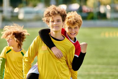 Futbol sahasının tepesinde gururla zaferlerini kutlayan bir grup genç adam. Ayaklarının altındaki parlak yeşil çimenler zaferlerini ve birlikteliklerini simgeliyor..