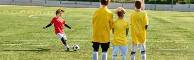 Bir grup genç adam, zorlu bir maçın ardından yüzleri gururla ışıldayarak bir futbol sahasının tepesinde muzaffer bir şekilde duruyorlar..