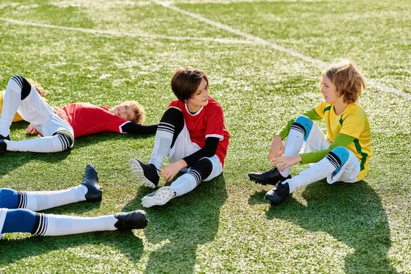 Group Young Children Gleefully Sit Atop Vibrant Soccer Field Chatting — Stock Photo, Image