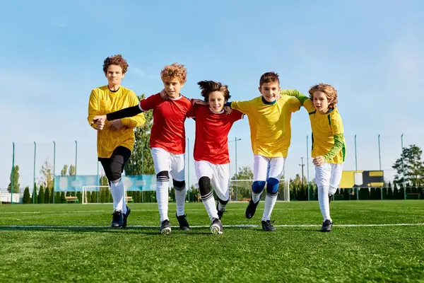 Canlı bir futbol maçına katılan bir grup genç adam sahada enerji ve takım çalışmasıyla mücadele ederken topa vuruyorlar..