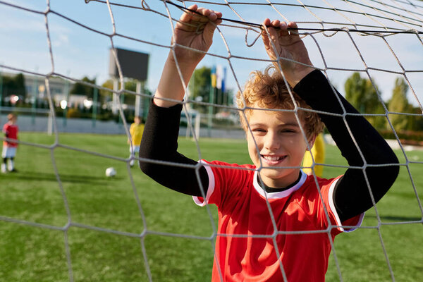 A young boy stands confidently in front of a soccer goal, focused on scoring a goal. His posture exudes determination and passion for the game, as he prepares to take a shot.
