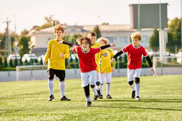 サッカーボールをエネルギッシュに蹴り回し 芝生場でゲームのスキルと情熱を披露する若い男の子のグループとして活気あふれるシーン — ストック写真