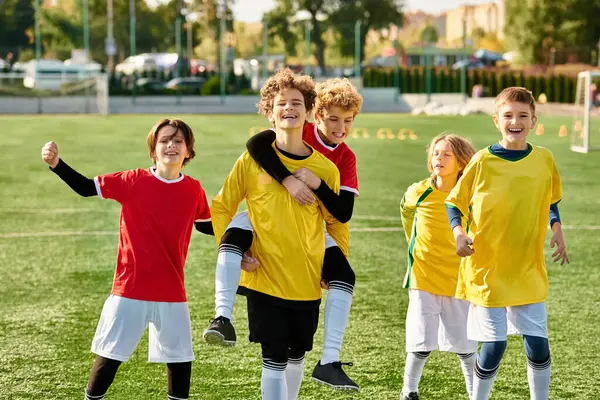 A group of young men celebrate their victory by standing triumphantly on top of a soccer field, enjoying the moment of accomplishment and camaraderie.