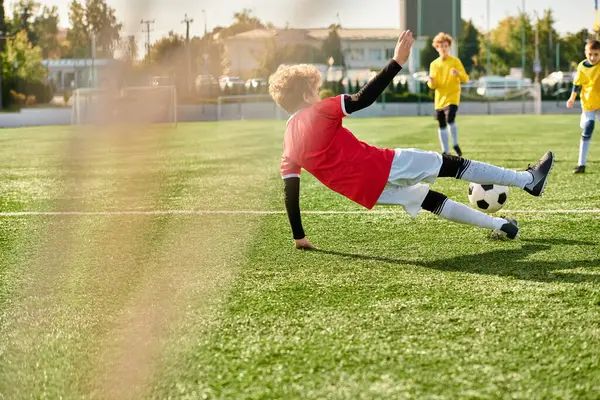 広大なグリーンフィールドにサッカーボールを蹴る決意のある表情を持つ少年は スポーツへの情熱とスキルを披露します — ストック写真