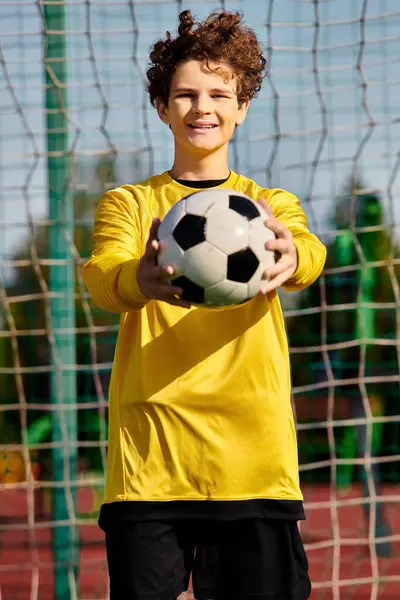 若い男がネットの前に立って サッカーボールを手に持って ショットを撮る準備をしている 彼は焦点を当てて 彼の視点で目標を決めている — ストック写真