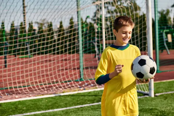 明るい黄色いサッカーのユニフォームを寄付する才能ある少年は自信を持ってサッカーボールを開催し 彼がゲームのために準備する情熱と決意を誇ります — ストック写真