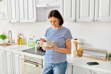 Konforlu bir ev elbisesi giymiş bir kadın mutfakta elinde bir kase tutuyor..