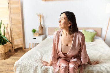 A mature woman in cozy homewear relaxing on a bed in a serene room. clipart