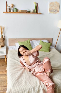 A mature woman in pink pajamas lays peacefully on a cozy bed. clipart