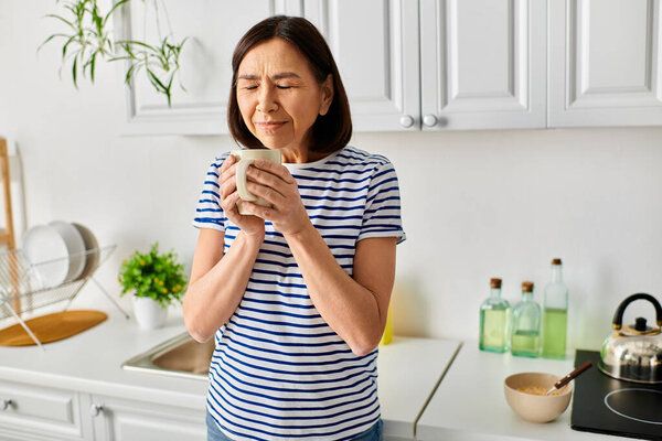 A cozy woman enjoying a cup of something in a tranquil kitchen setting.