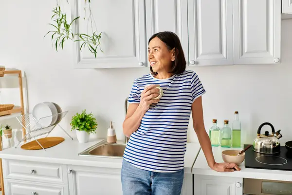 居心地の良いホームウェアの成熟した女性は キッチンシンクによって立っています — ストック写真
