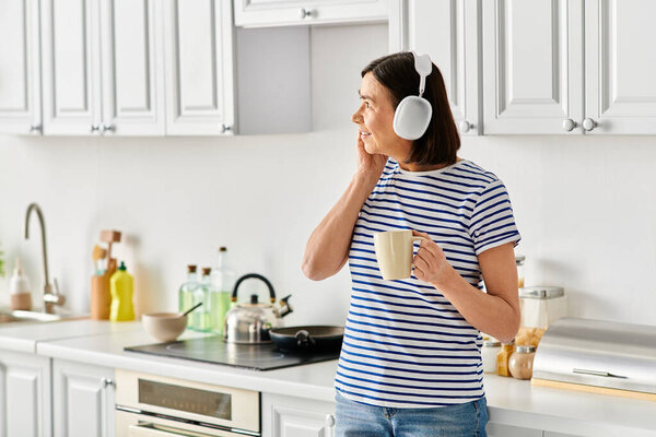 Mature woman in cozy homewear enjoys a cup of coffee in the kitchen.