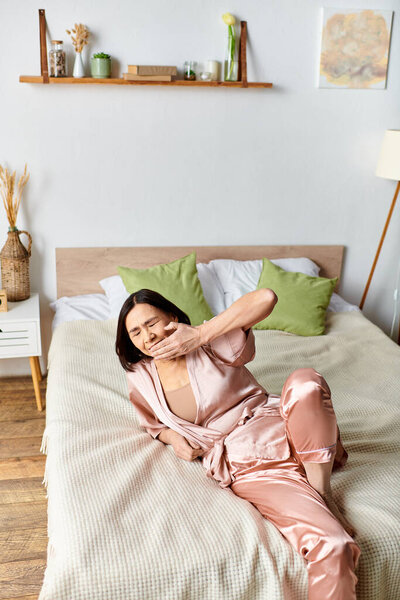 A mature woman in pink pajamas lays peacefully on a cozy bed.