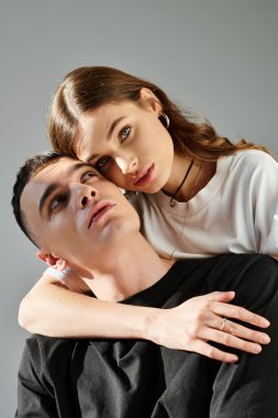 A young man and woman, deeply in love, elegantly pose together for a picture in a studio with a grey background. clipart