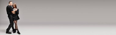 Tarafsız gri bir arkaplan önünde genç bir çift bir arada duruyor..