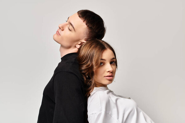 A young couple standing side by side in a studio with a grey background, expressing love and togetherness.