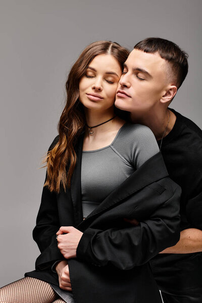 Мужчина и женщина сидят рядом друг с другом, глаза наполнены любовью и спокойствием, на сером фоне студии.