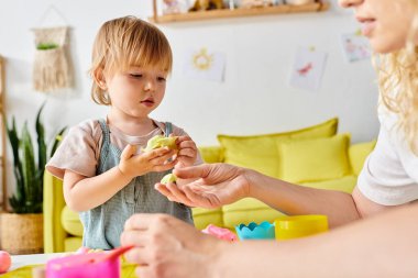 Kıvırcık saçlı bir anne ve küçük kızı evde Montessori oyuncaklarıyla oynaşıyor..