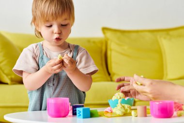 Anne ve küçük kızı Montessori 'de oyun oynuyorlar ve evde öğreniyorlar, küçük bir masada oyuncakları birlikte keşfediyorlar..
