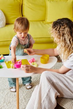 Kıvırcık saçlı bir anne ve küçük kızı evde Montessori eğitimini kullanarak oyuna daldılar..