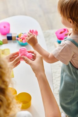 Kıvırcık bir anne ve küçük kızı renkli bir hamurla Montessori 'de elle öğreniyorlar..