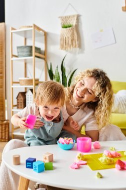 Kıvırcık bir anne ve küçük kızı evde Montessori eğitim oyuncaklarıyla oynuyorlar, yaratıcılığı teşvik ediyorlar ve öğreniyorlar..