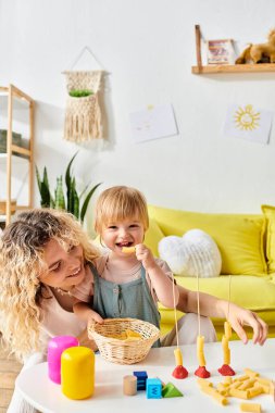 Curly mother and toddler daughter immersed in Montessori education at home. clipart