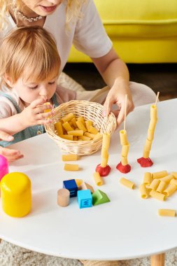 Kıvırcık saçlı bir anne ve küçük kızı evde Montessori eğitim oyuncaklarıyla oynuyorlar..