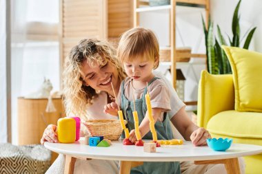 Kıvırcık bir anne ve küçük kızı evde çeşitli oyuncaklarla Montessori 'nin tadını çıkarıyorlar..
