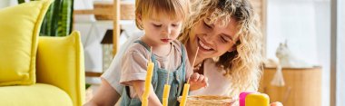 Kıvırcık bir anne ve küçük kızı evde Montessori eğitim yöntemini kullanarak birlikte oynuyorlar..