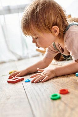 Yerde oyuncaklarla oynayan, yaratıcılığı ve öğrenmeyi keşfeden küçük bir çocuk..