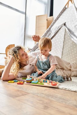 Anne ve bebek yerde Montessori oyuncaklarıyla oynuyorlar..