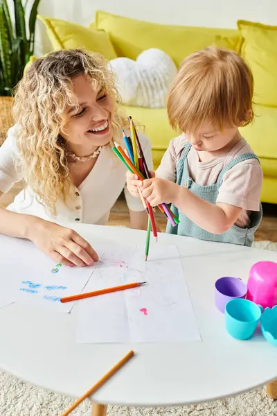 stock image A curly mother and her toddler daughter bonding over crayons using the Montessori method of education at home.