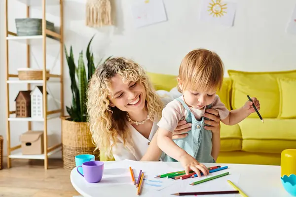 Curly Haired Mother Her Toddler Daughter Sit Table Surrounded Crayons — Stock Photo, Image