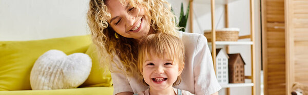 Кудрявая мать и ее маленькая дочь разделяют весёлый момент Монтессори дома..