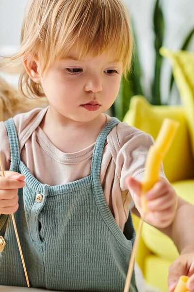 Маленькая девочка держит сухую пасту и исследует сенсорную игру