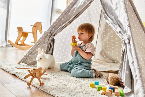 A small child engrossed in play with toys inside a vibrant play tent, using the Montessori method.
