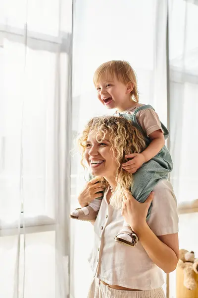 stock image A curly-haired mother cradles her toddler daughter lovingly in her arms at home.