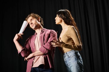 A man and a woman stand confidently against a black backdrop. clipart