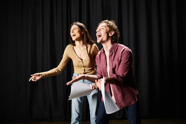 Элегантный мужчина и женщина позируют перед черным занавесом.