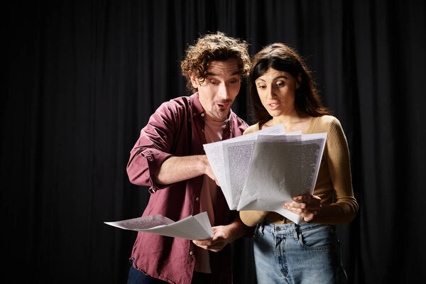 Handsome man stands beside woman holding papers, rehearsing for theater performance.