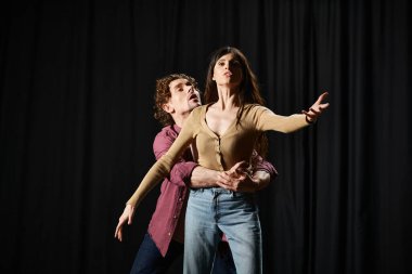 A man and woman stand before a black curtain, preparing for a theatrical performance. clipart